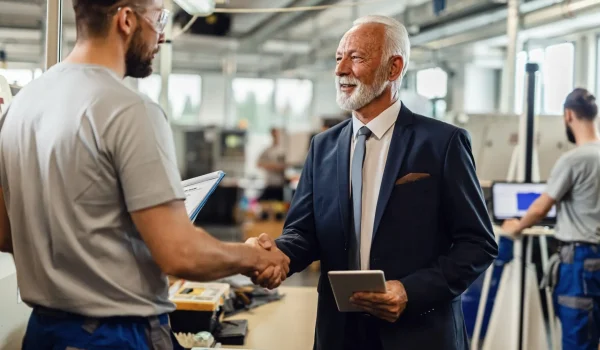 Foto de uma negociação B2B acontecendo no ambiente industrial, representada por dois homens apertando as mãos.